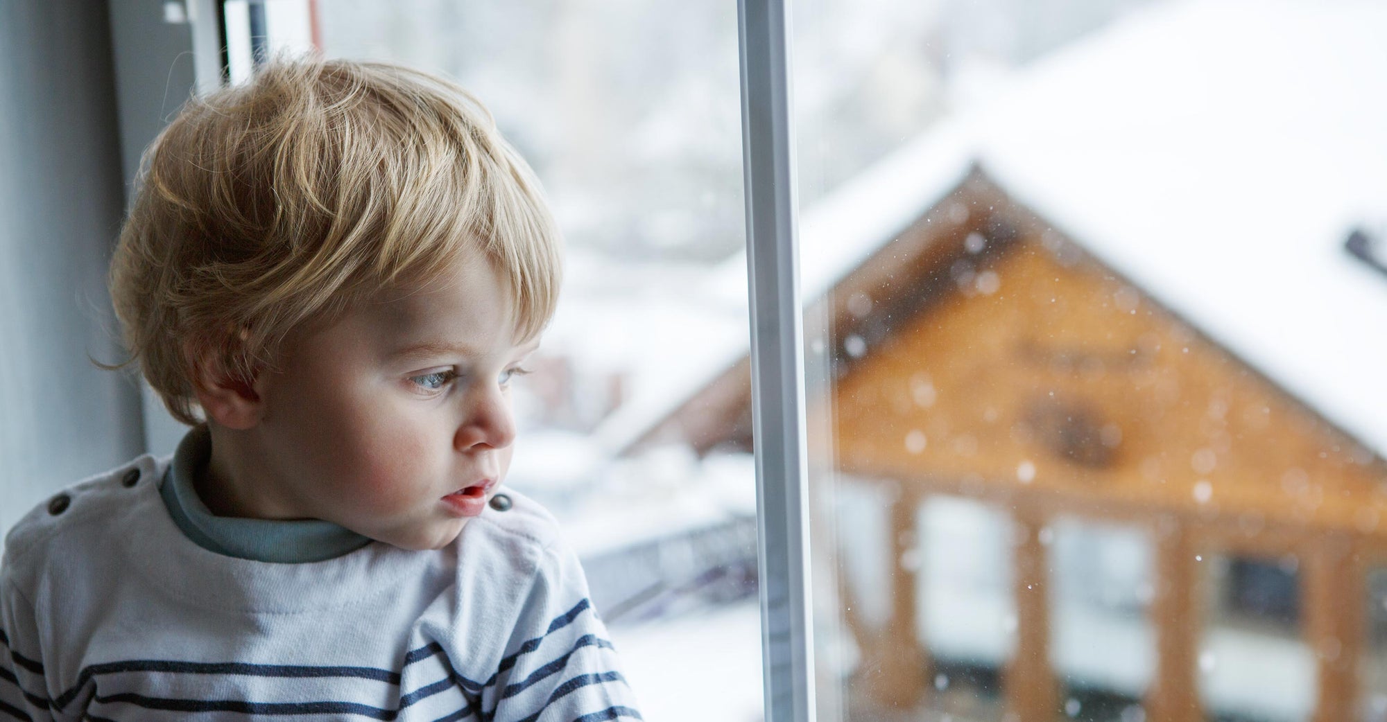 child staring outside window snow outside
