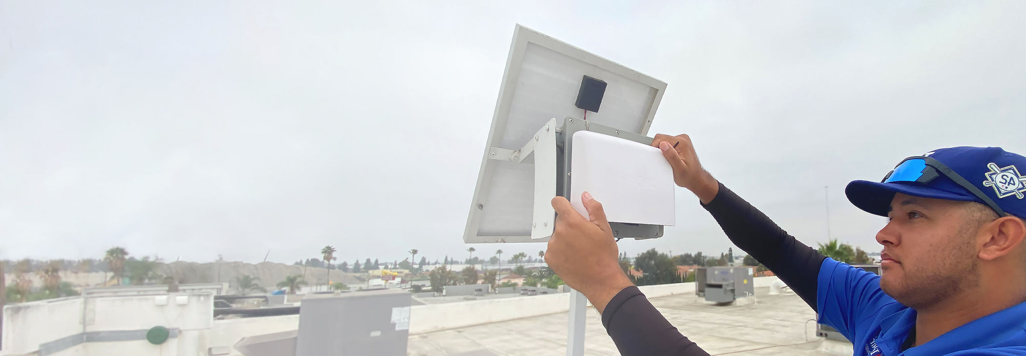 person installing IQAir&#039;s AirVisual Outdoor below a solar panel