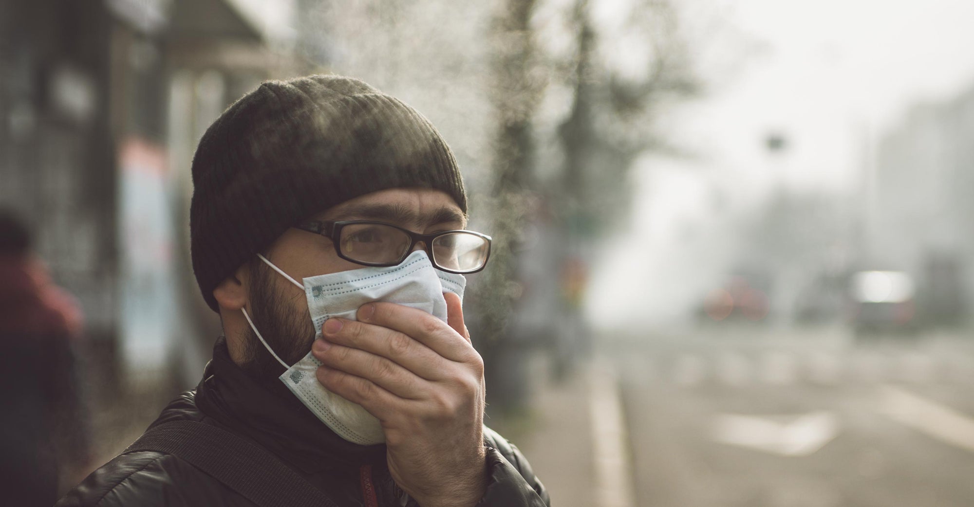 Man in city coughing with face mask