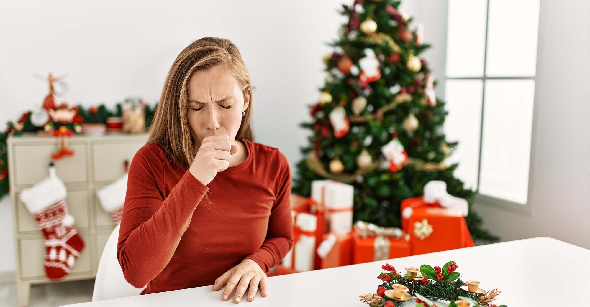 Woman coughing next to christmas tree