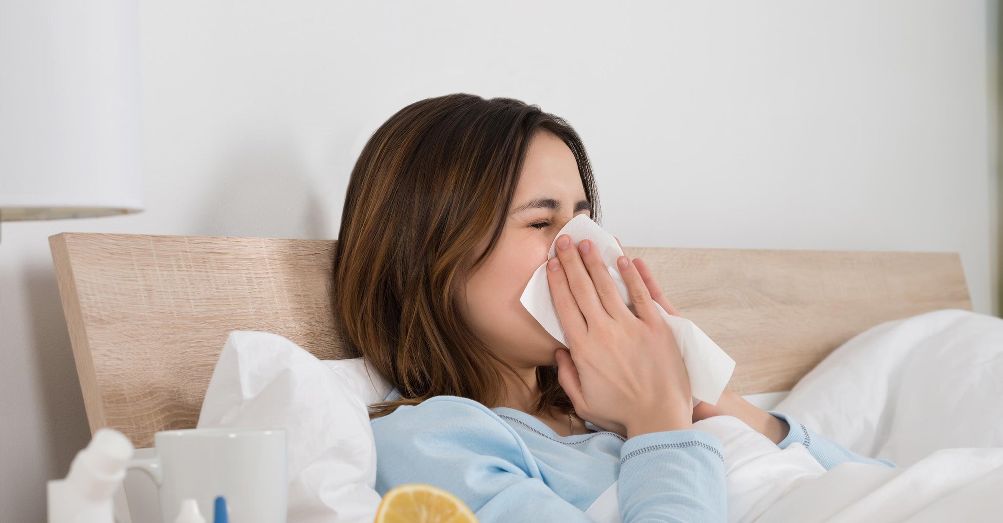 A woman with the flu is blowing her nose.