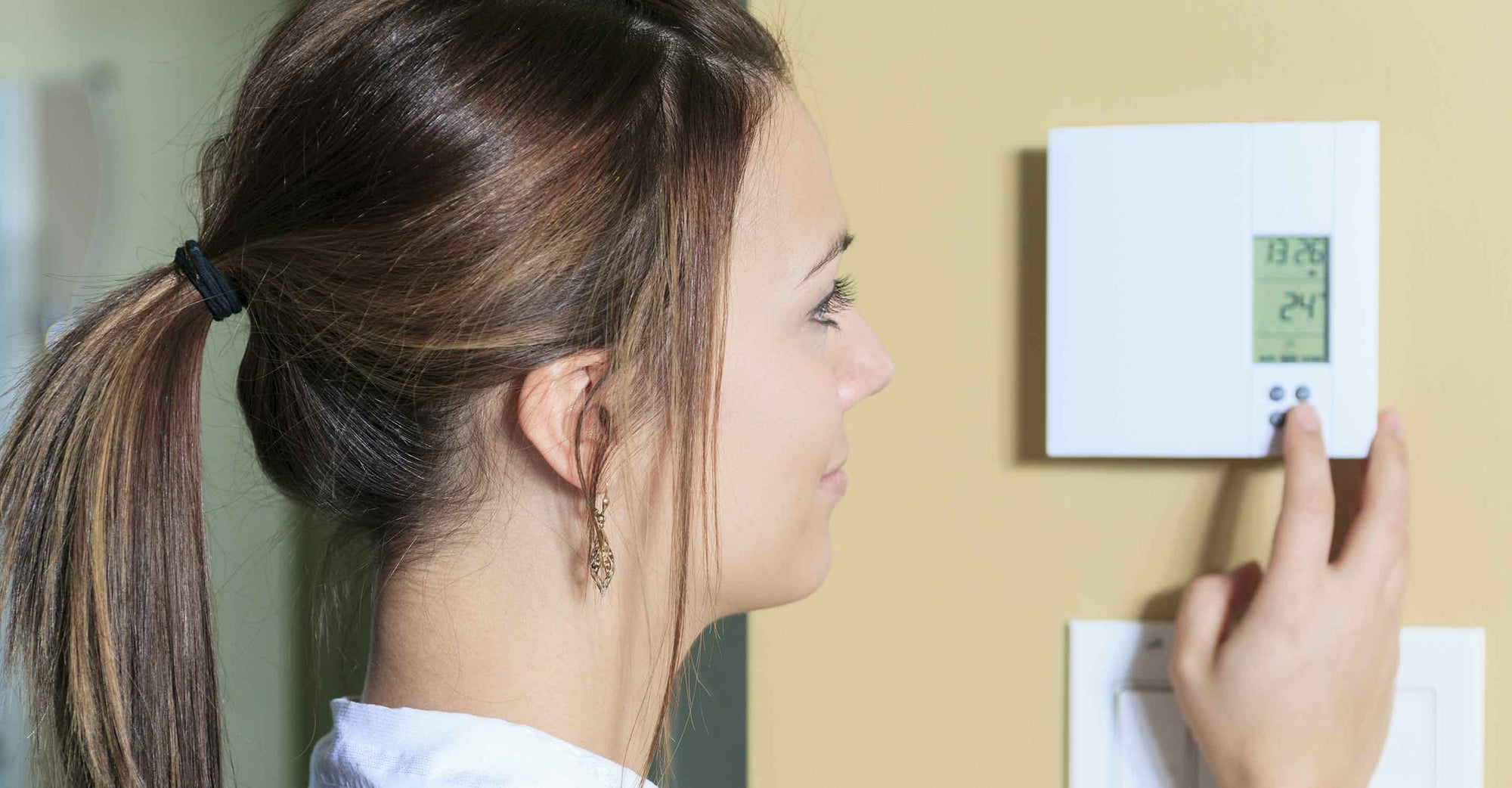 Young woman adjusting home thermostat