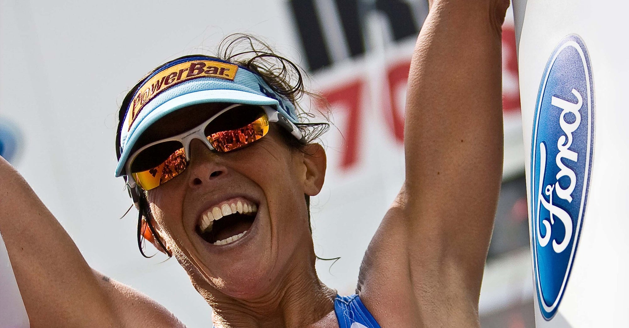 Lisa Bentley triumphantly smiling at the finish of a race