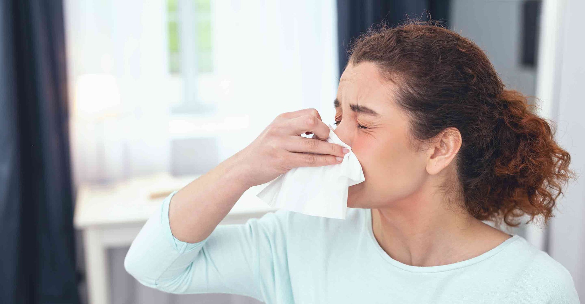 Woman with allergies blows her nose