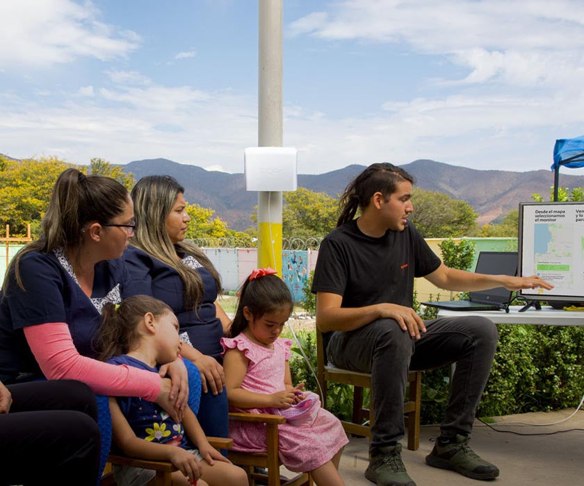 Group of people viewing computer screen with AirVisual Outdoor in background.