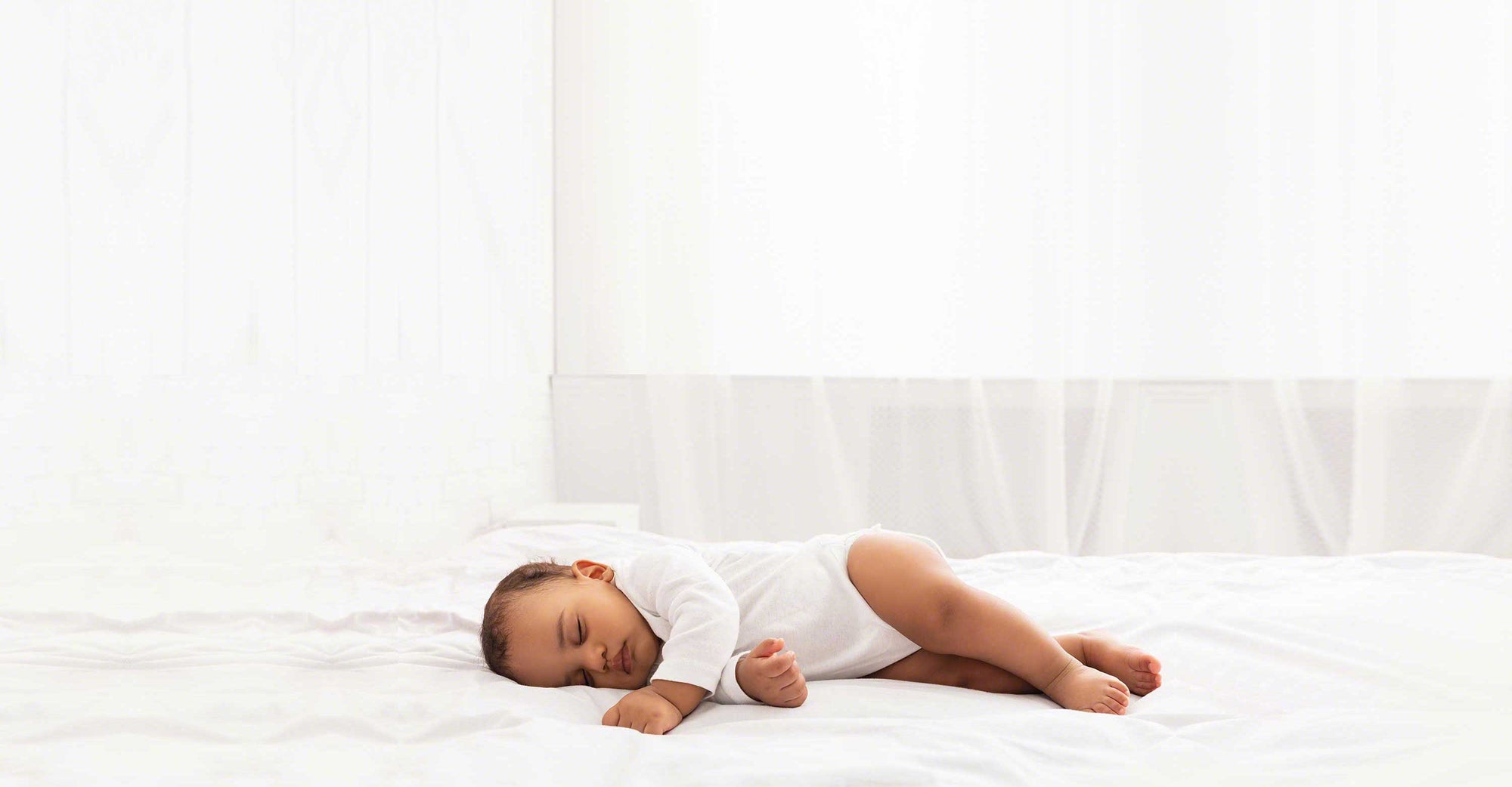 baby laying in large white bed