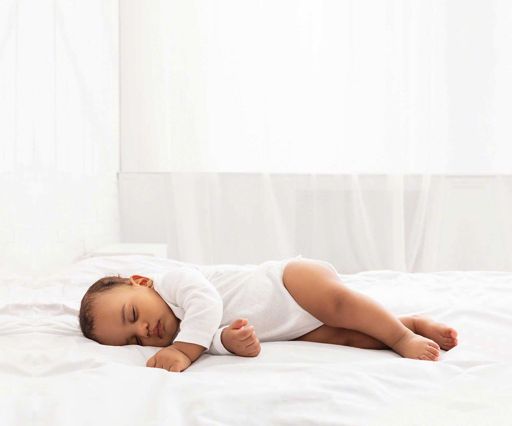 baby laying in large white bed